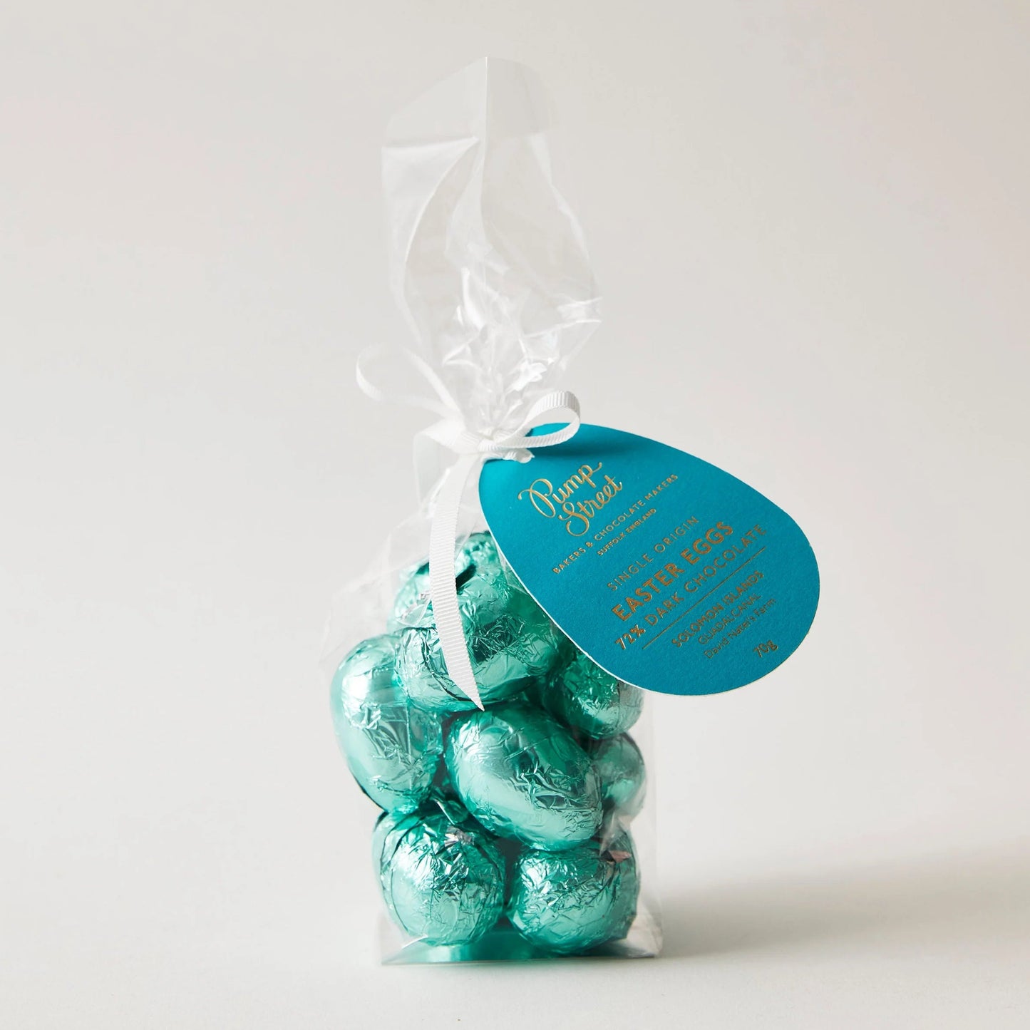 A bag of teal foil-wrapped pump street solomon islands 72% chocolate easter eggs tied with a white ribbon and blue tag
