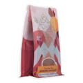 A vibrant pink and white bag of ariana’s cozy cabin blend ritual drinking chocolate 55 percent with geometric orange accents