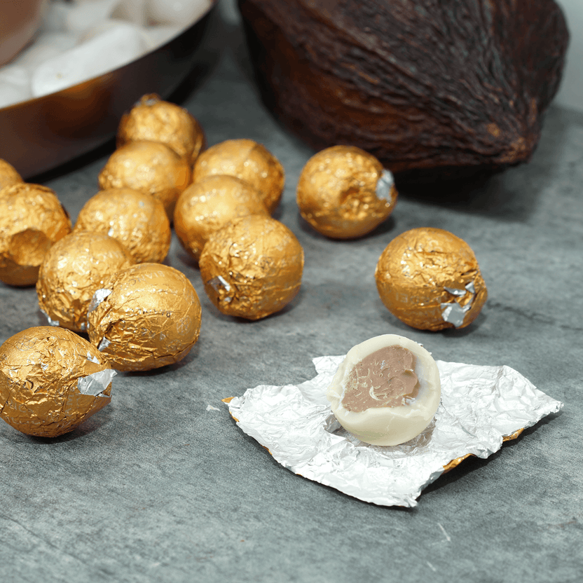 Amedei Pralines White w/ Hazelnut Filling: golden foil-wrapped truffles, one unwrapped showing white shell and dark center
