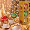 Auro Chocobomb hot chocolate gift set next to cups of hot chocolate, with a lit Christmas tree behind.