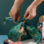 Hands tying Bar & Cocoa cotton furoshiki wrap around a chocolate gift
