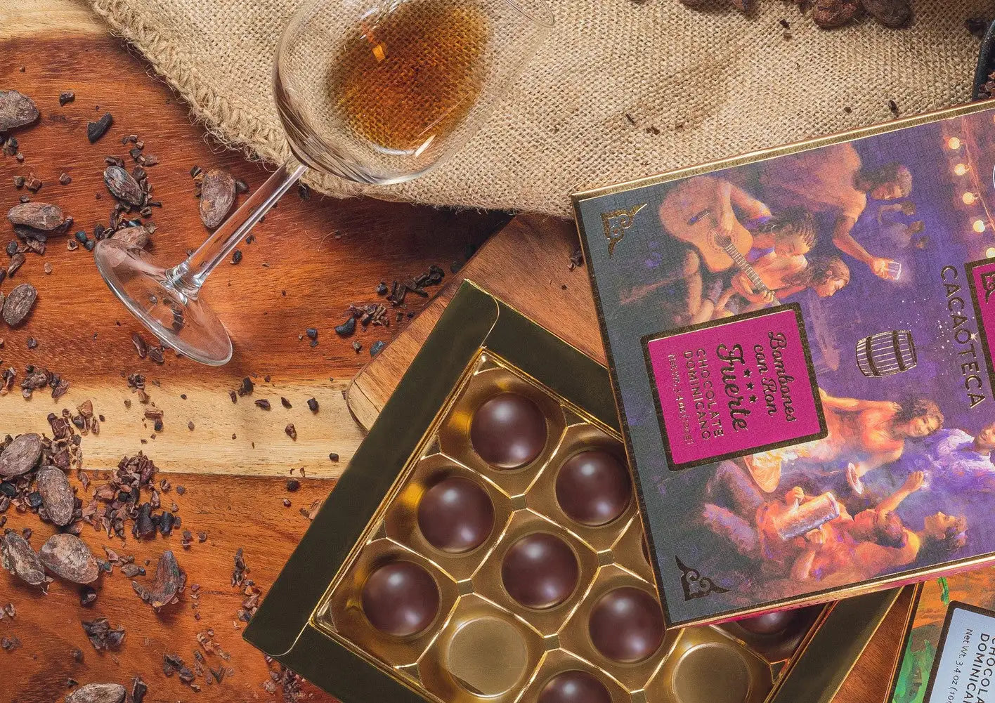 A box of dark chocolate truffles in a gold foil-lined tray, featuring an illustrated label with purple and pink accents.