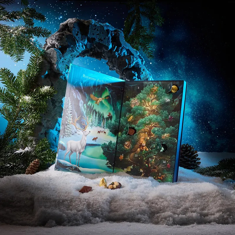 Opened Cluizel chocolate advent calendar book set in snow with chocolates resting in front.