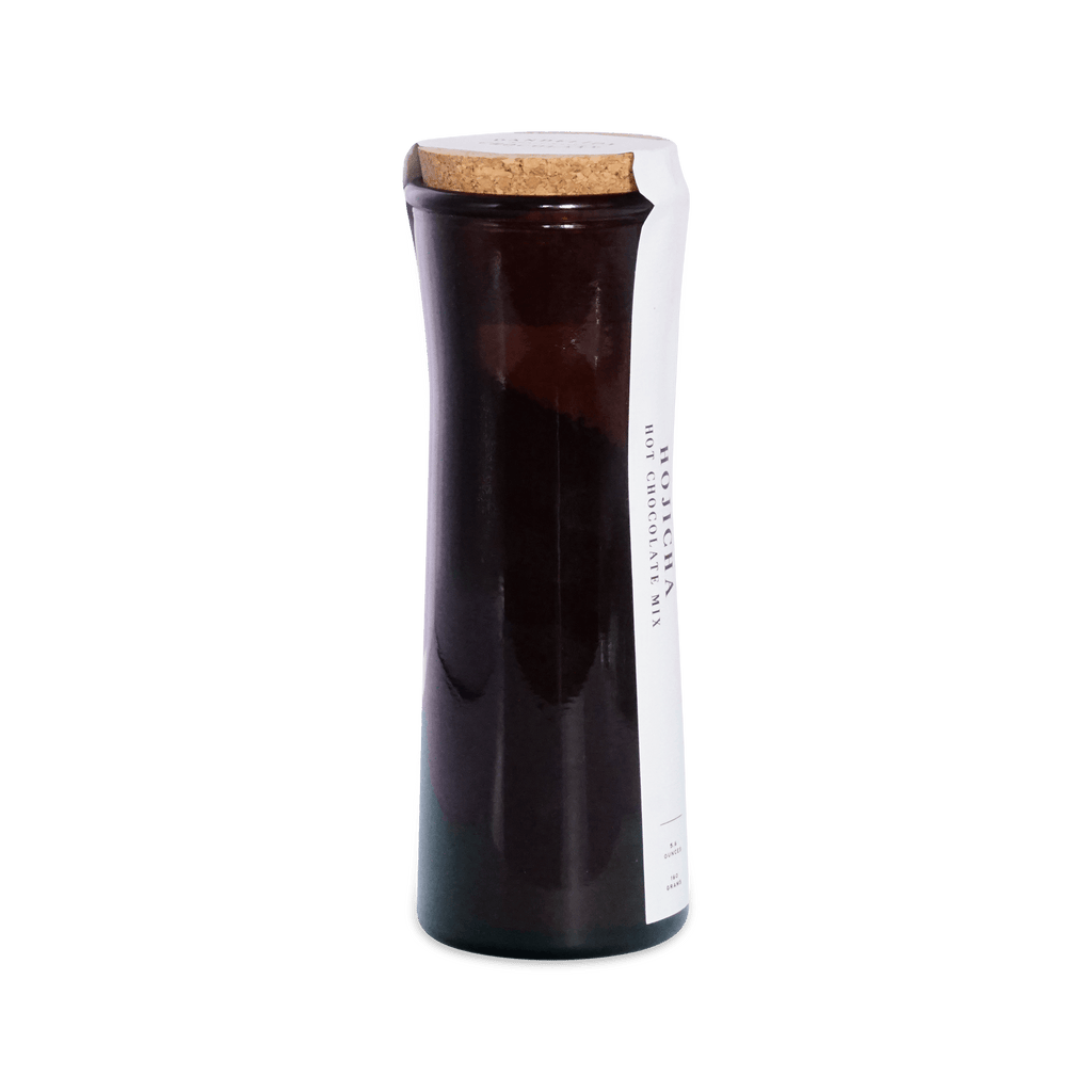 Angled view of the dark amber Hojicha Hot Chocolate Mix jar with a cork lid and white wraparound label.