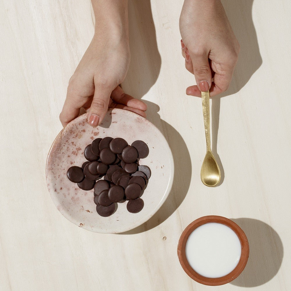 Domori Bulk Dark Chuao 75% drops on speckled off-white ceramic plate