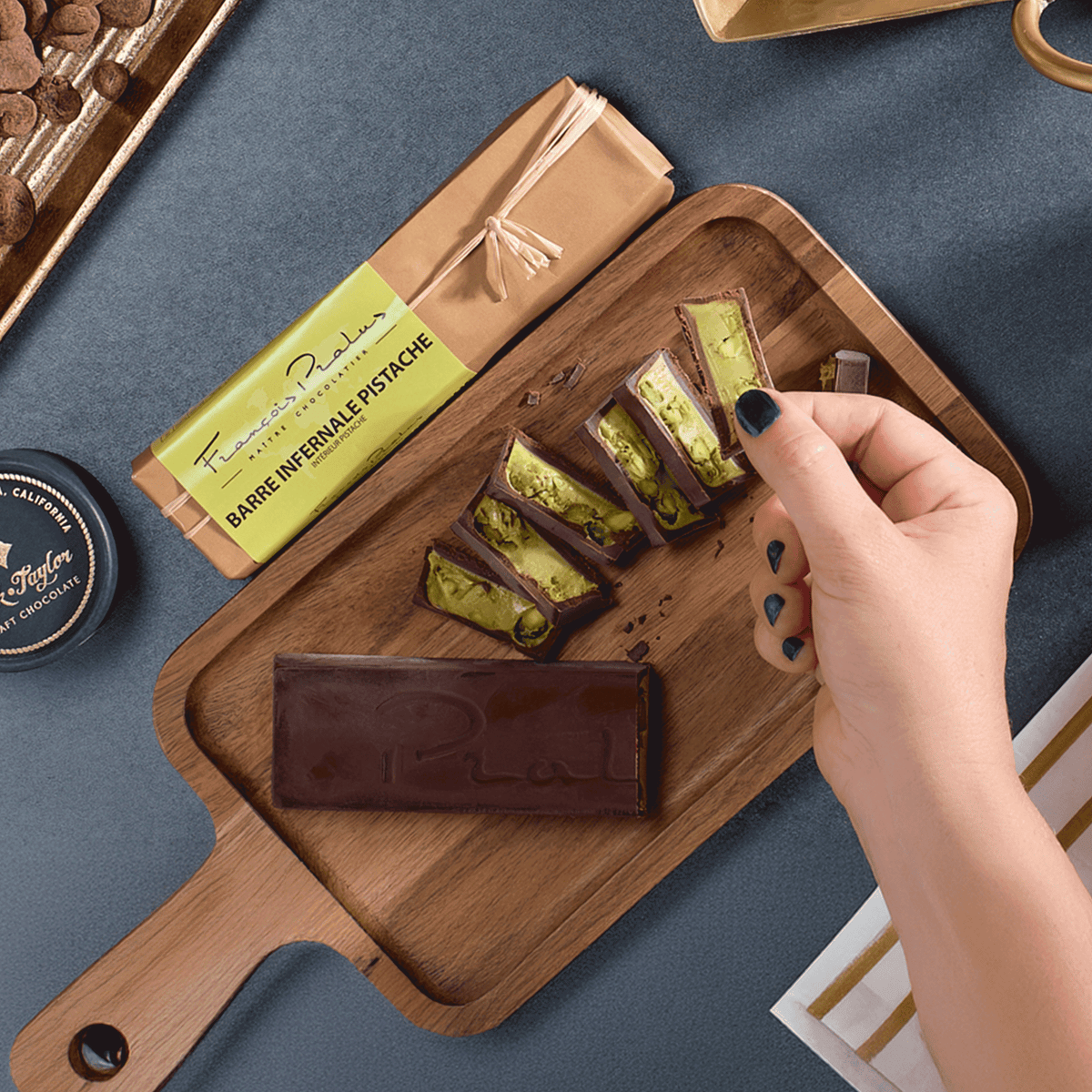 Hand picking a sliced Pralus pistachio bar from a wooden board