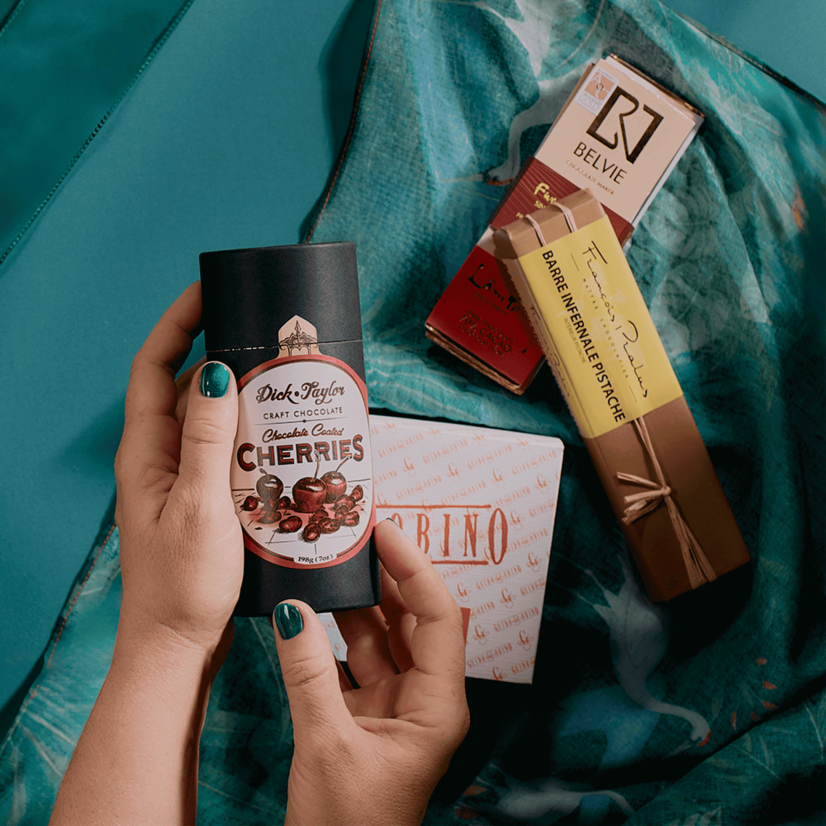 Hands holding Dick Taylor chocolate-coated cherries with Belvie, Pralus and Guido Gobino chocolates