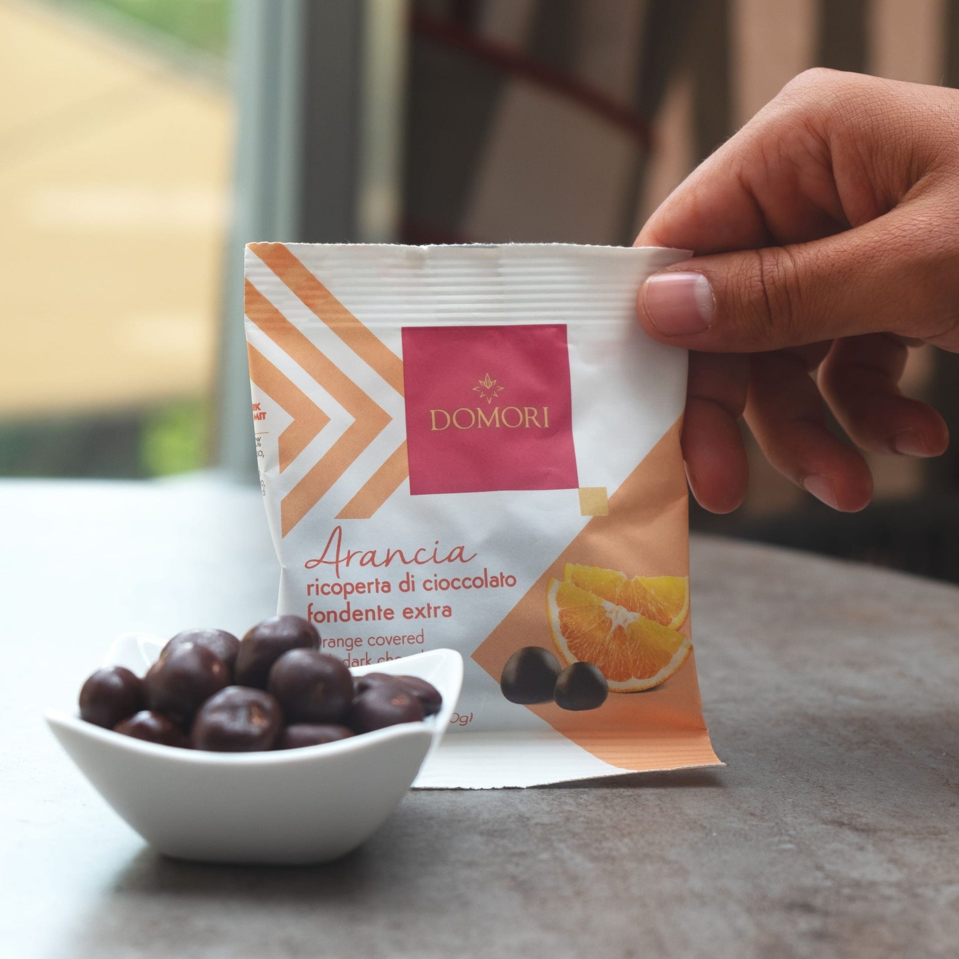 Domori Dragees chocolate covered orange packet in hand