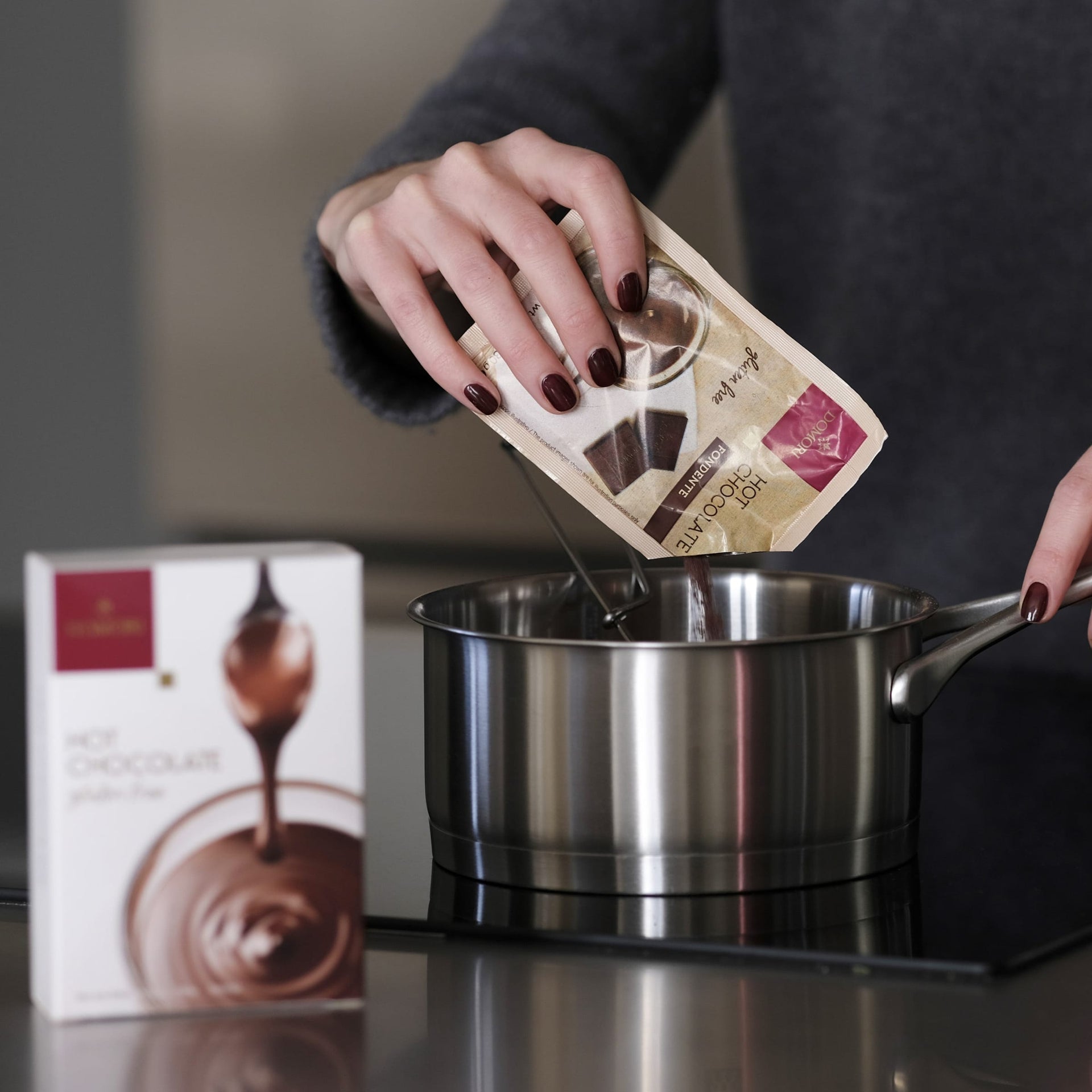 Pouring Domori Hot Chocolate Mix from beige pink packet into saucepan