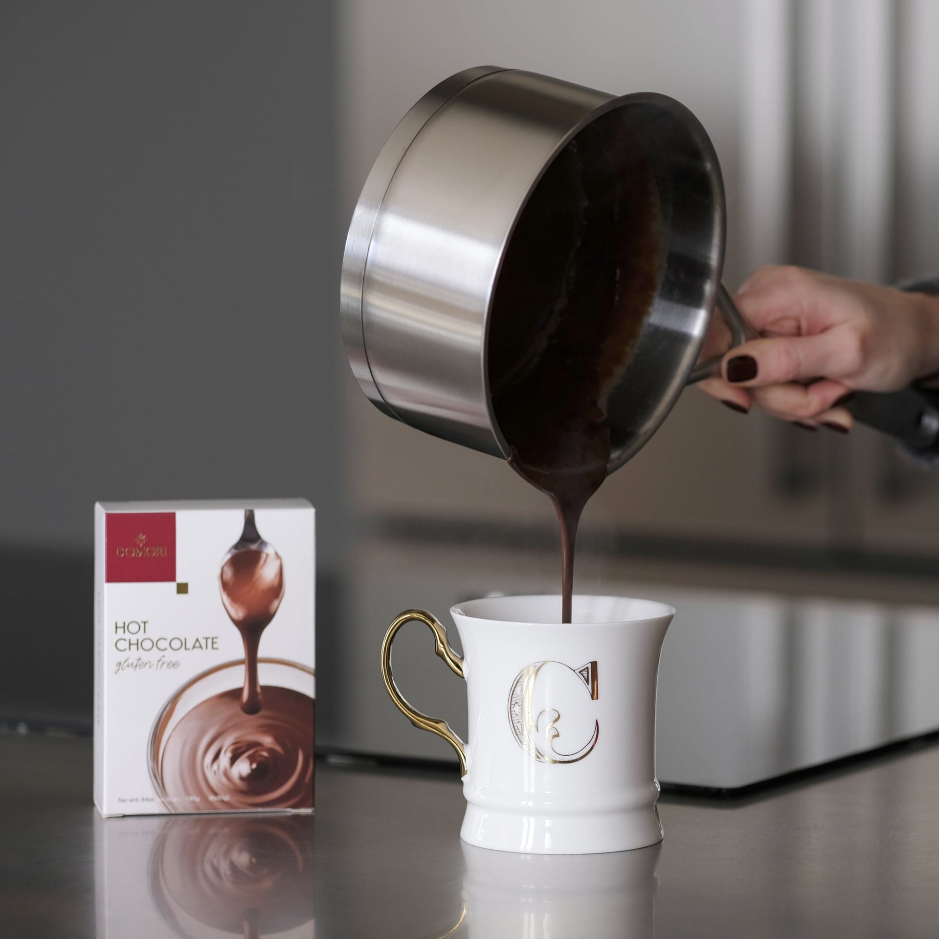 White ceramic Domori Hot Chocolate mug with gold handle and silver C monogram