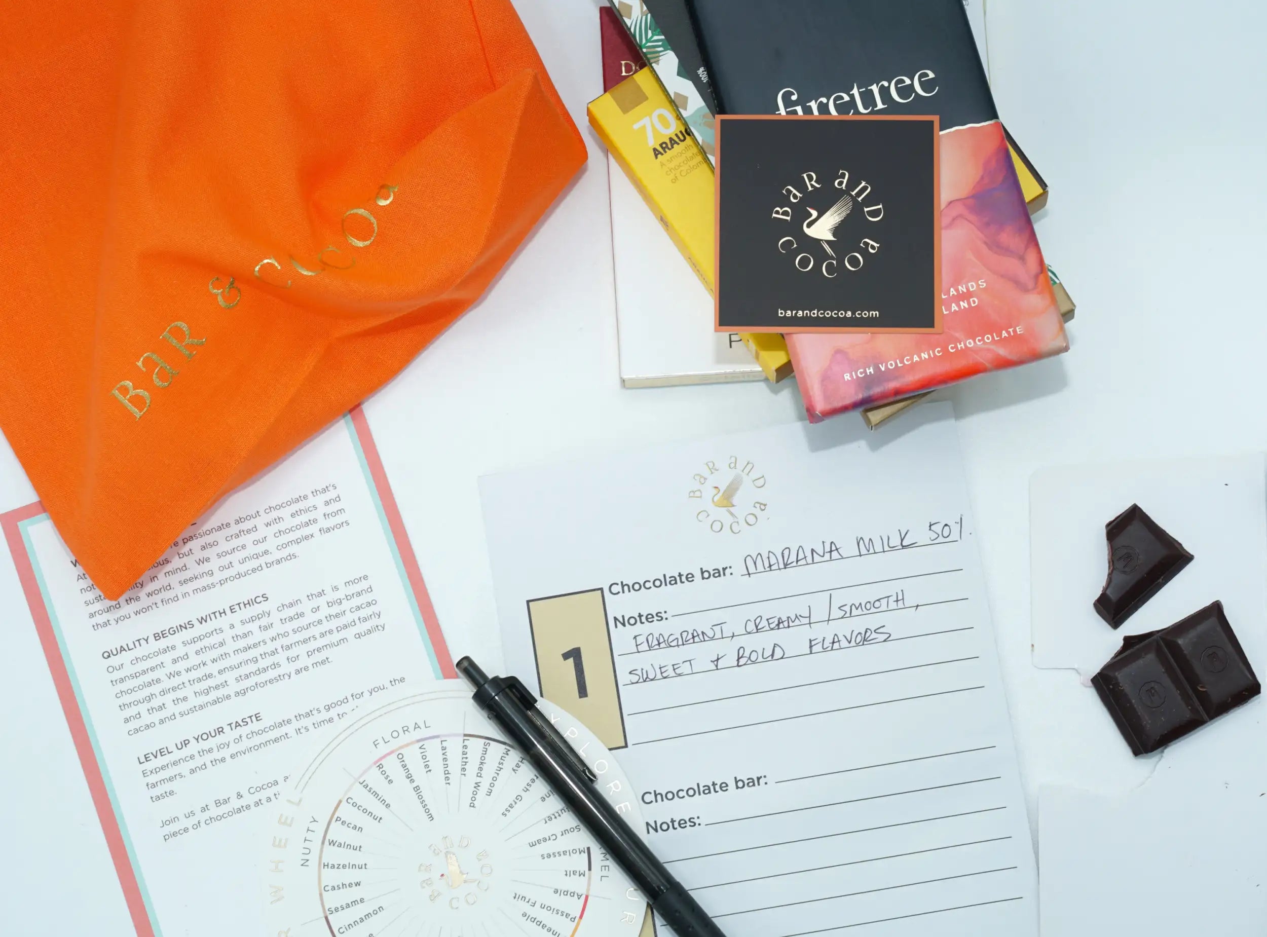 Orange paper bag with gold foil lettering reading ’bar & cocoa’