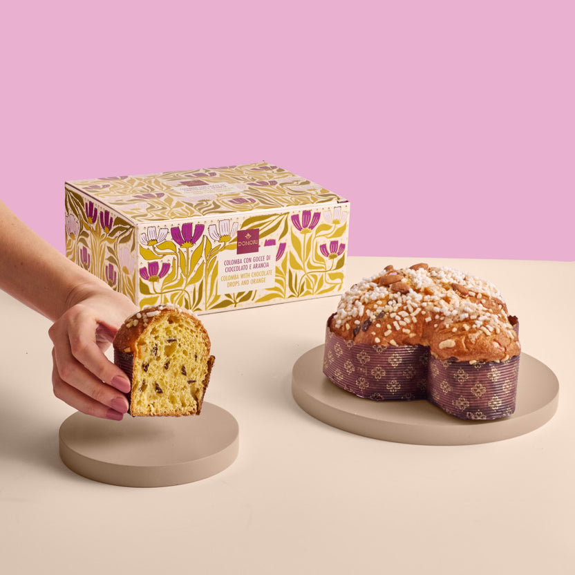 A golden-brown sliced Domori Easter cake with candied orange peel chocolate pieces and white sugar sprinkles
