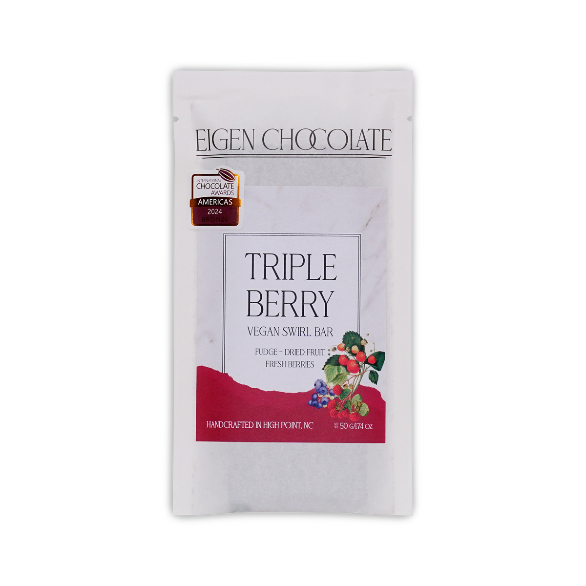 White Eigen Chocolate pouch with a red panel and a berry sprig, reading Triple Berry Vegan Swirl Bar, with a 2024 awards seal.