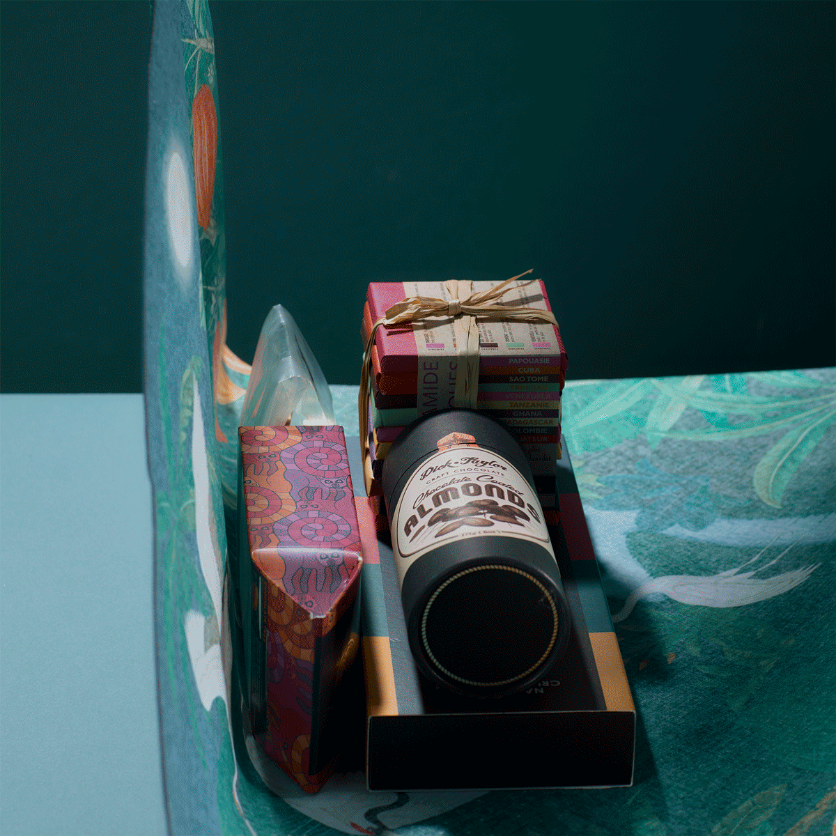 Hands wrapping and tying a chocolate bundle in Bar & Cocoa crane forest print furoshiki