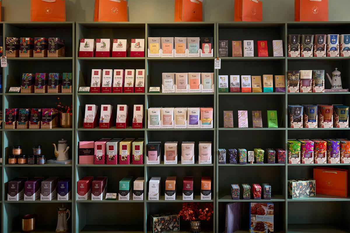 Green shelves stocked with craft chocolate bars from makers around the world