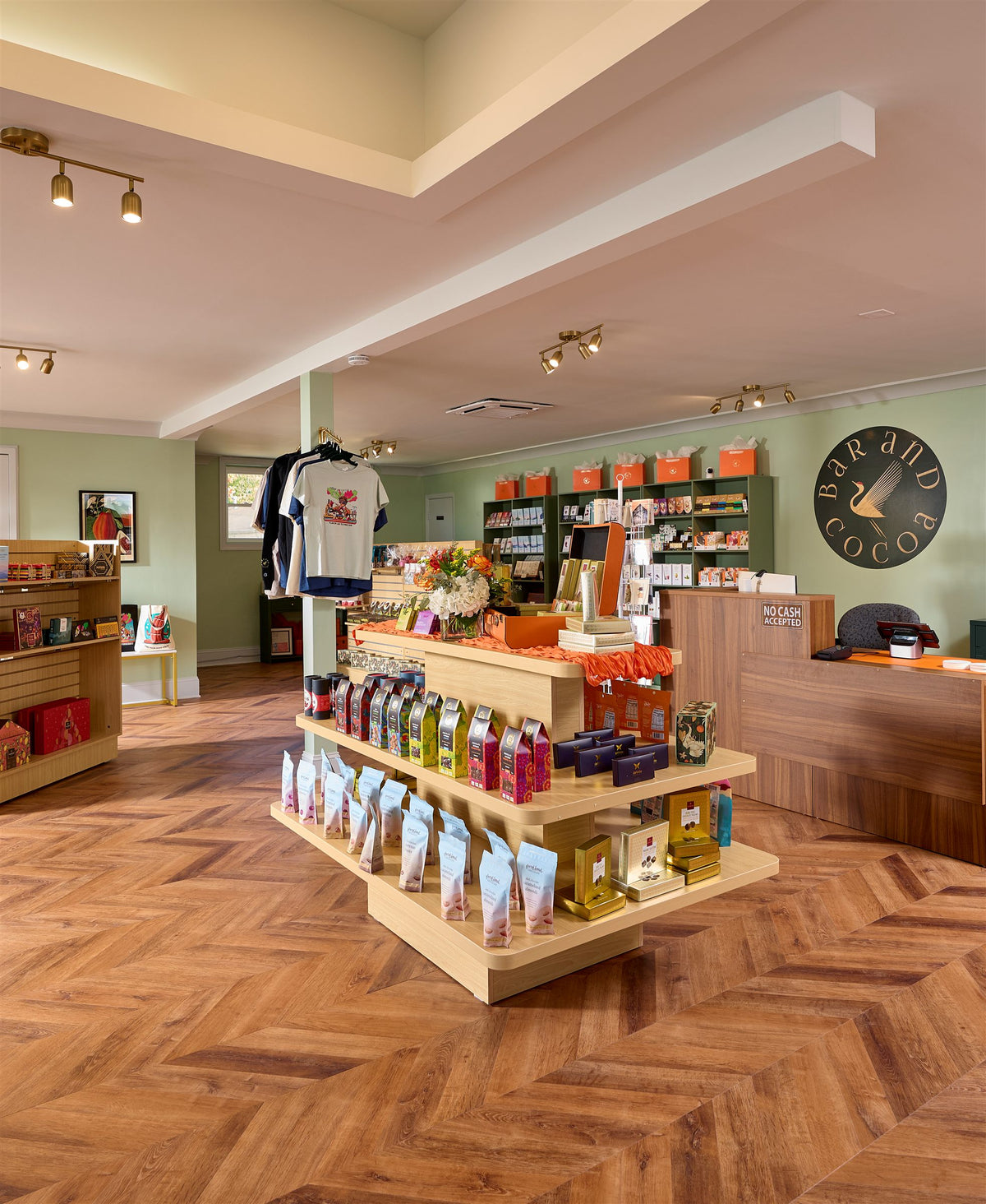 Inside the Bar & Cocoa Greensboro shop: wood floors, chocolate displays, and green shelving