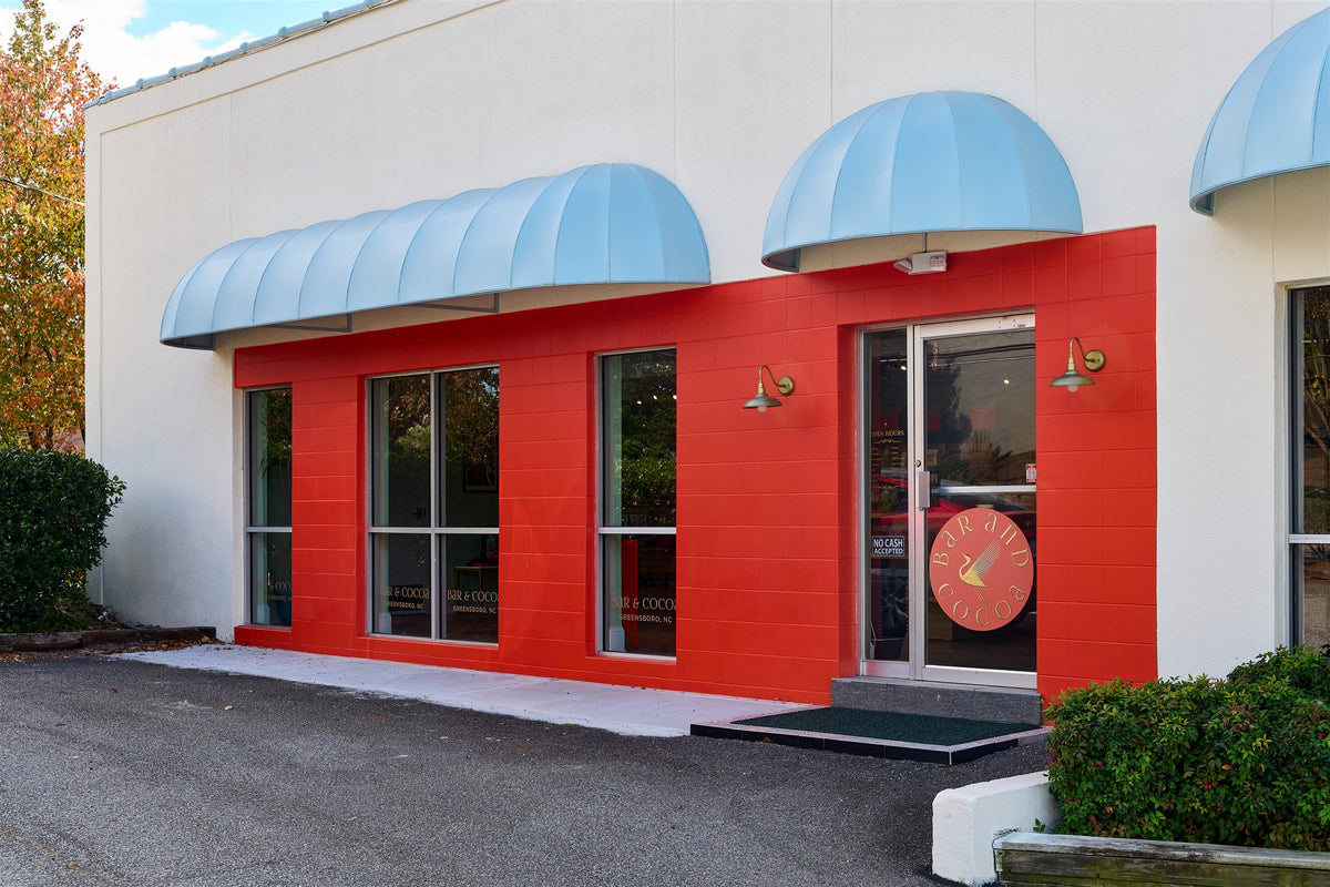 Bar & Cocoa storefront in Greensboro, NC, with a red facade, blue awnings, and a glass front door