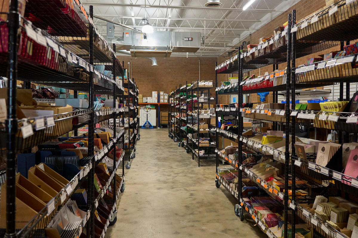Warehouse aisle with shelves of chocolate where Bar & Cocoa online orders are packed