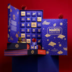 Open blue Marou advent calendar beside its gold-printed lid, with chocolate pieces and gift boxes on a red background