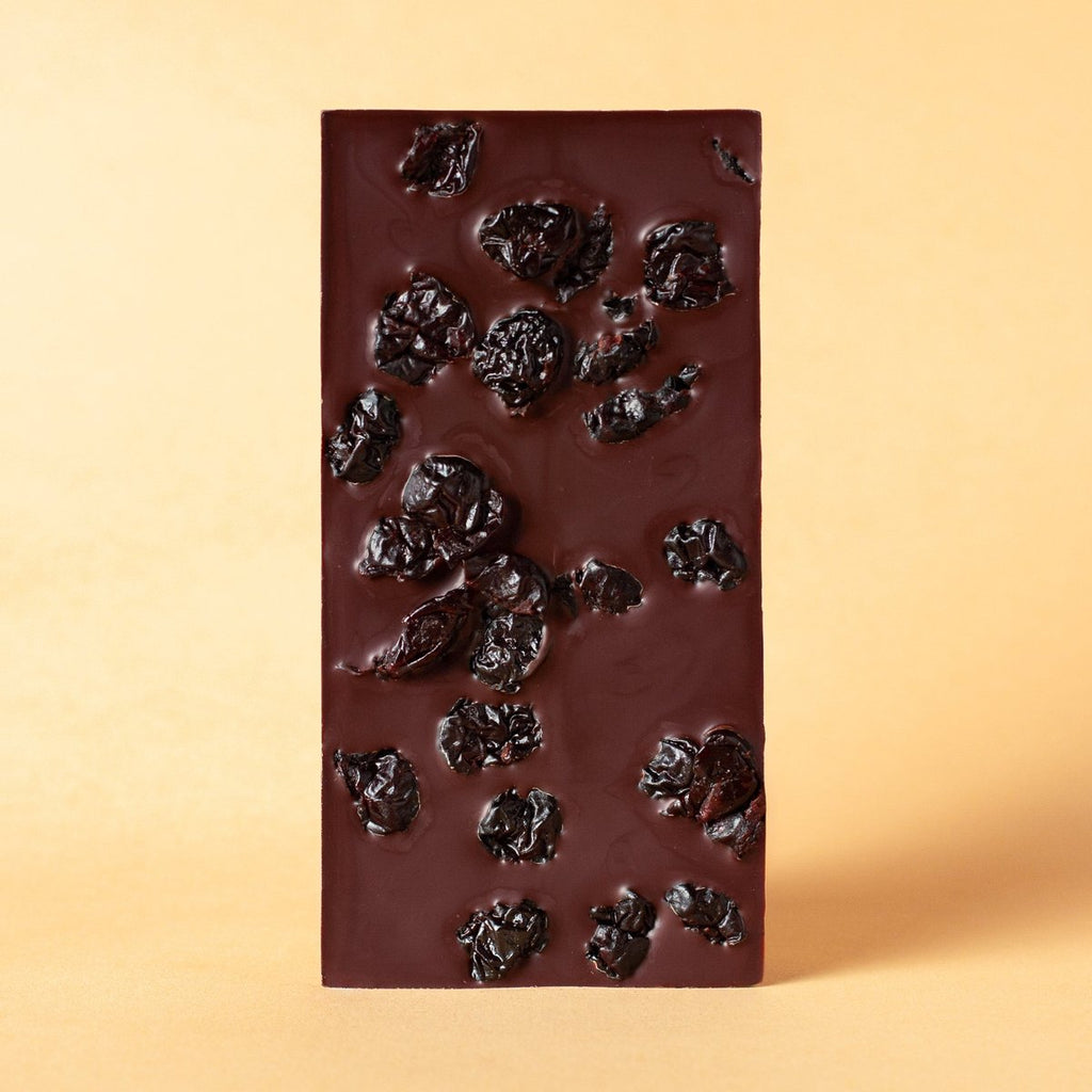 Unwrapped Moka Cherry 72% dark chocolate bar with whole cherries on a warm beige background