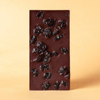 Unwrapped Moka Cherry 72% dark chocolate bar with whole cherries on a warm beige background