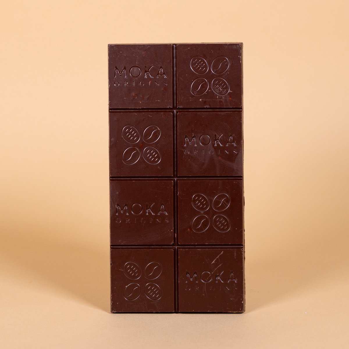 Unwrapped Moka Quinoa Crunch Milk Chocolate 58% bar on a warm beige background