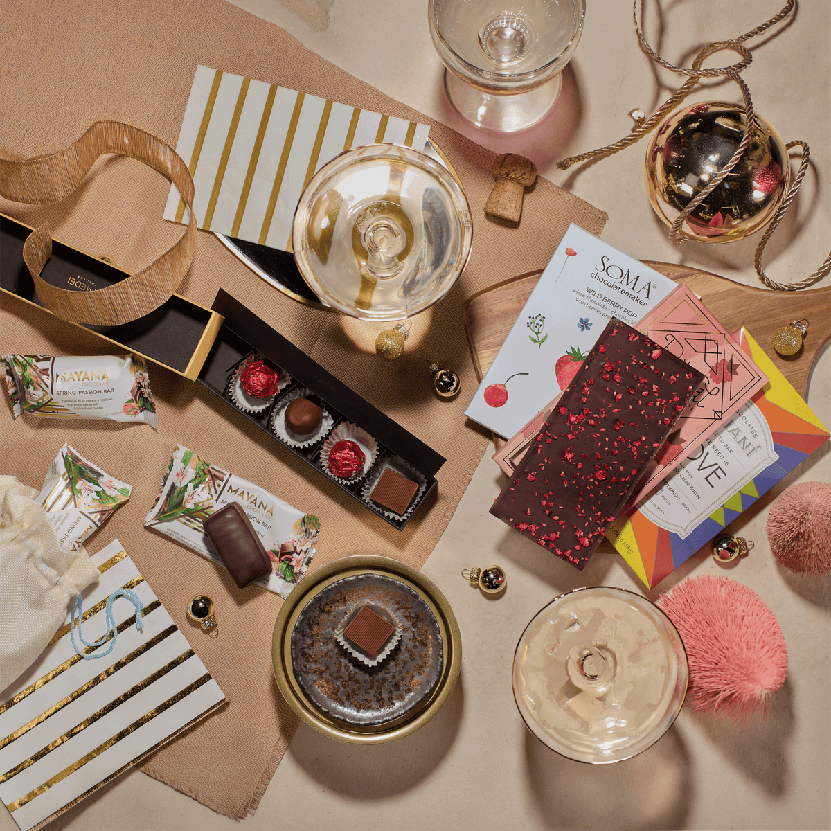 Flat lay of Pop, Clink, Cocoa celebration chocolates with sparkling wine glasses