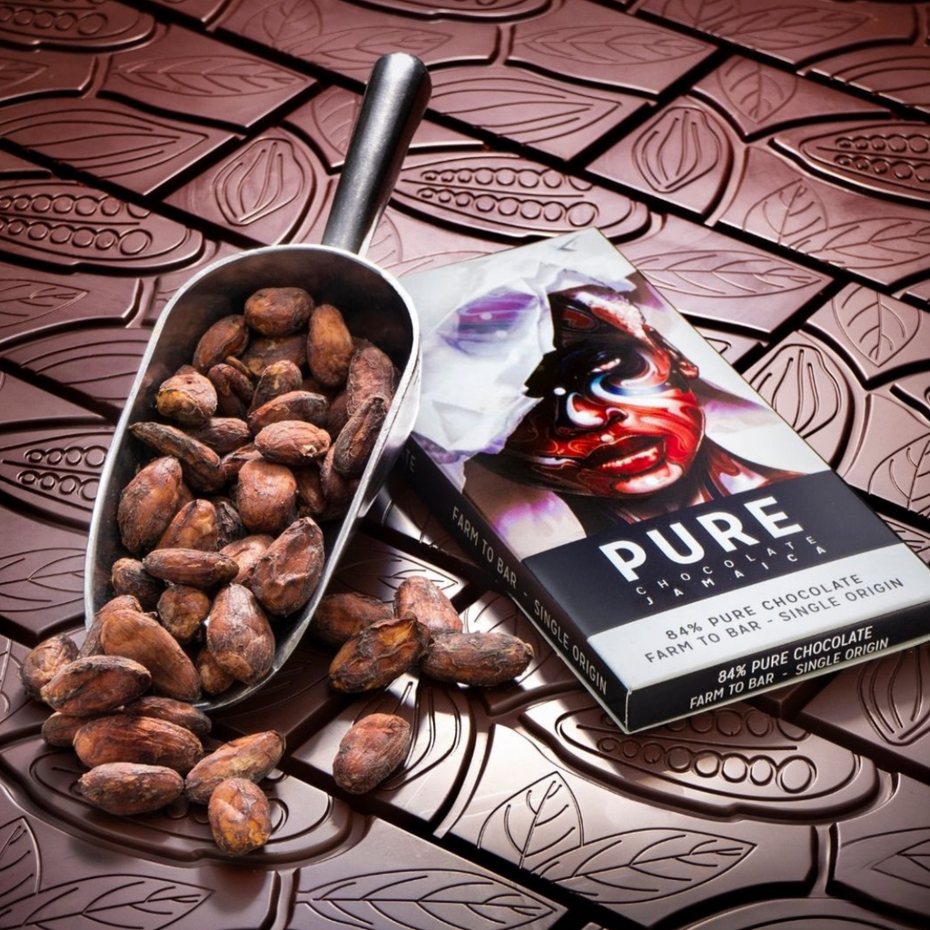 Sleek metallic scoop of cocoa beans beside Pure Chocolate Dark 84% bar