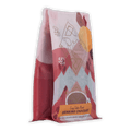 A vibrant pink and white bag of ariana’s cozy cabin blend ritual drinking chocolate 55 percent with geometric orange accents