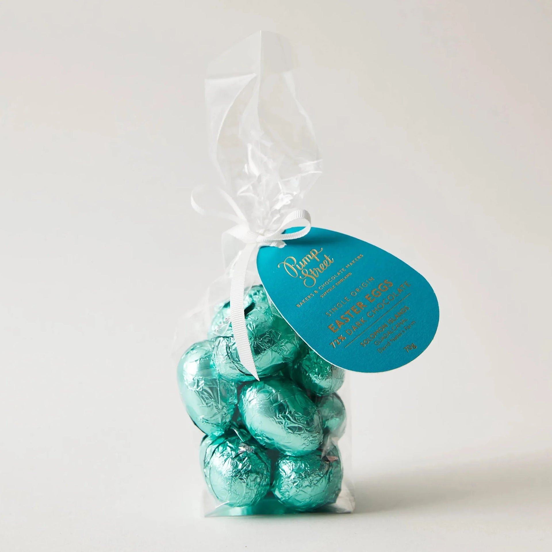 A bag of teal foil-wrapped pump street solomon islands 72% chocolate easter eggs tied with a white ribbon and blue tag