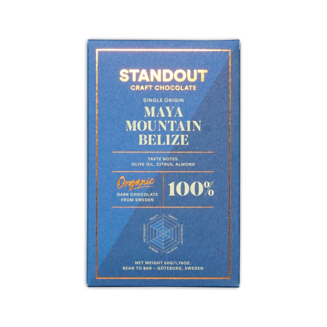 A sleek blue rectangular bar wrapper for Standout Chocolate Belize Maya Mountain 100% dark craft chocolate with gold foil lettering and a hexagonal flavor diagram