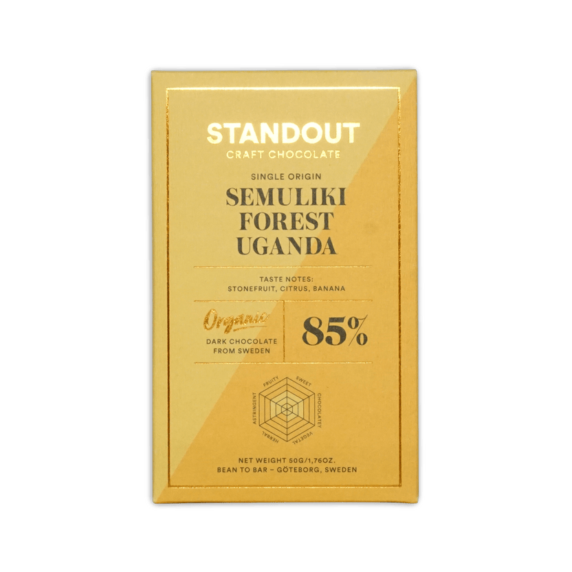 A golden-yellow rectangular chocolate bar wrapper from standout craft chocolate with gold foil lettering and a hexagonal flavor diagram for uganda semuliki forest 85 percent