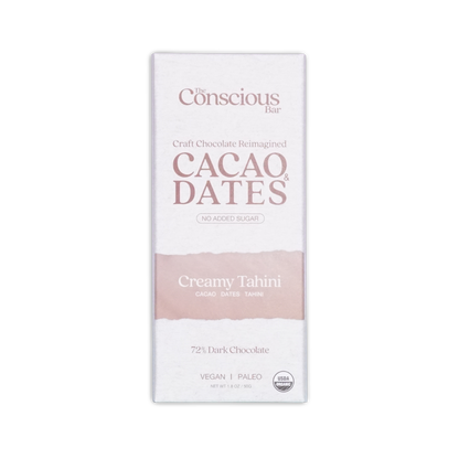 A white rectangular package of the conscious bar dark creamy tahini 72 percent cacao and dates chocolate bar with pink stripe