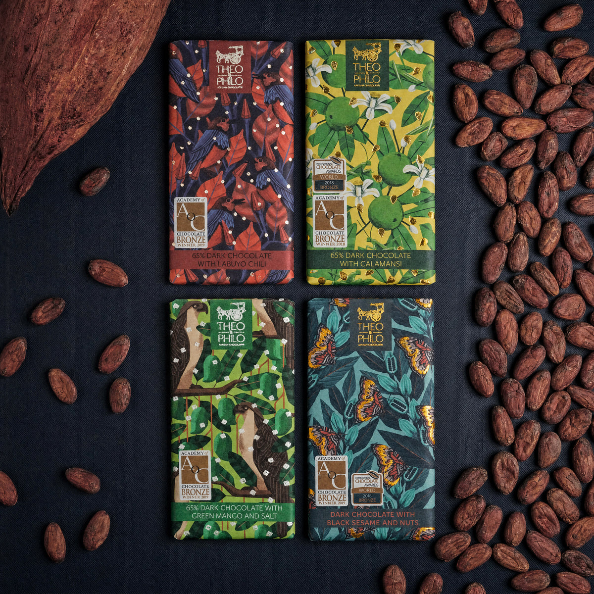 Four Theo & Philo dark bars with cacao beans.