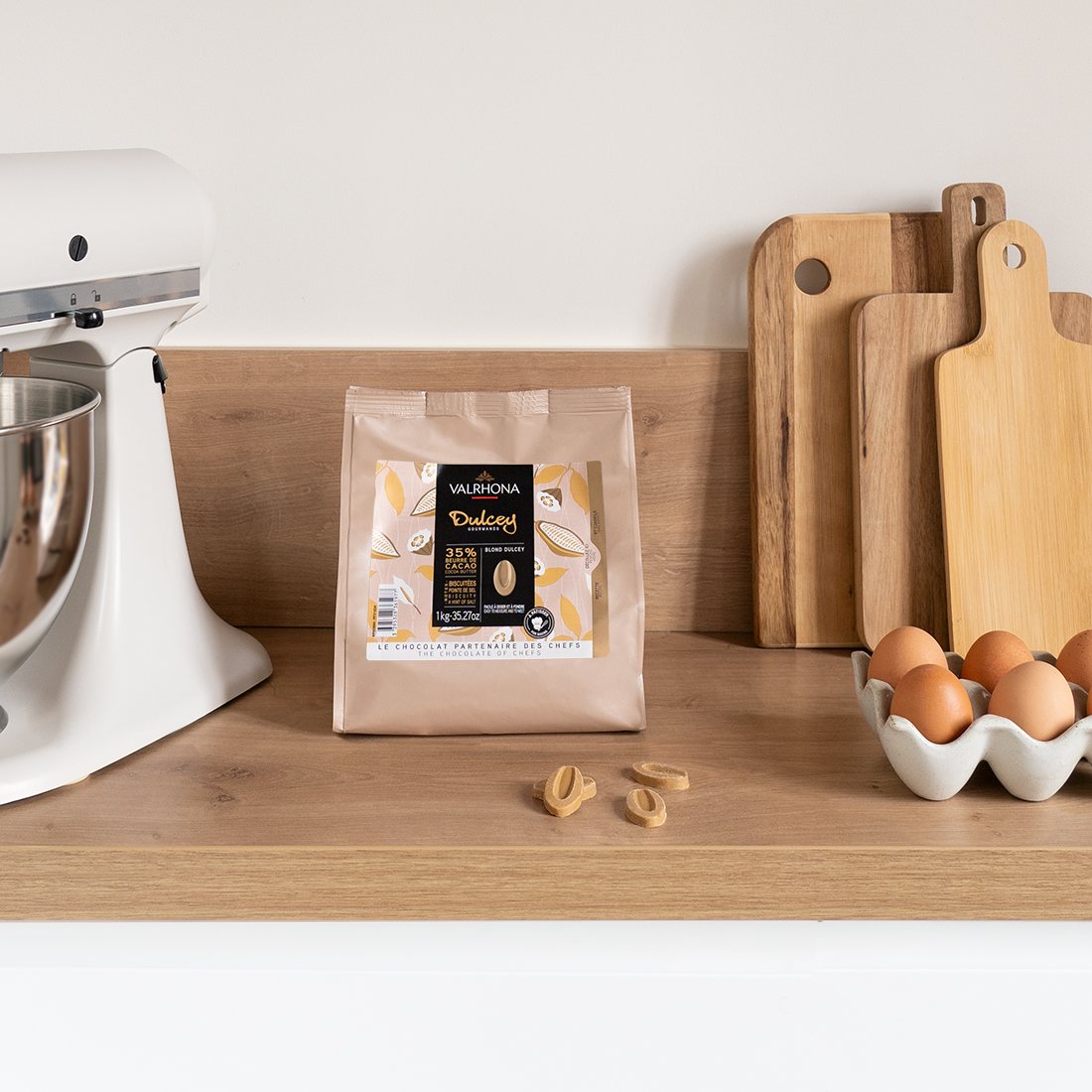 Valrhona Dulcey 35% blond chocolate feves pouch on a kitchen counter with a stand mixer and eggs