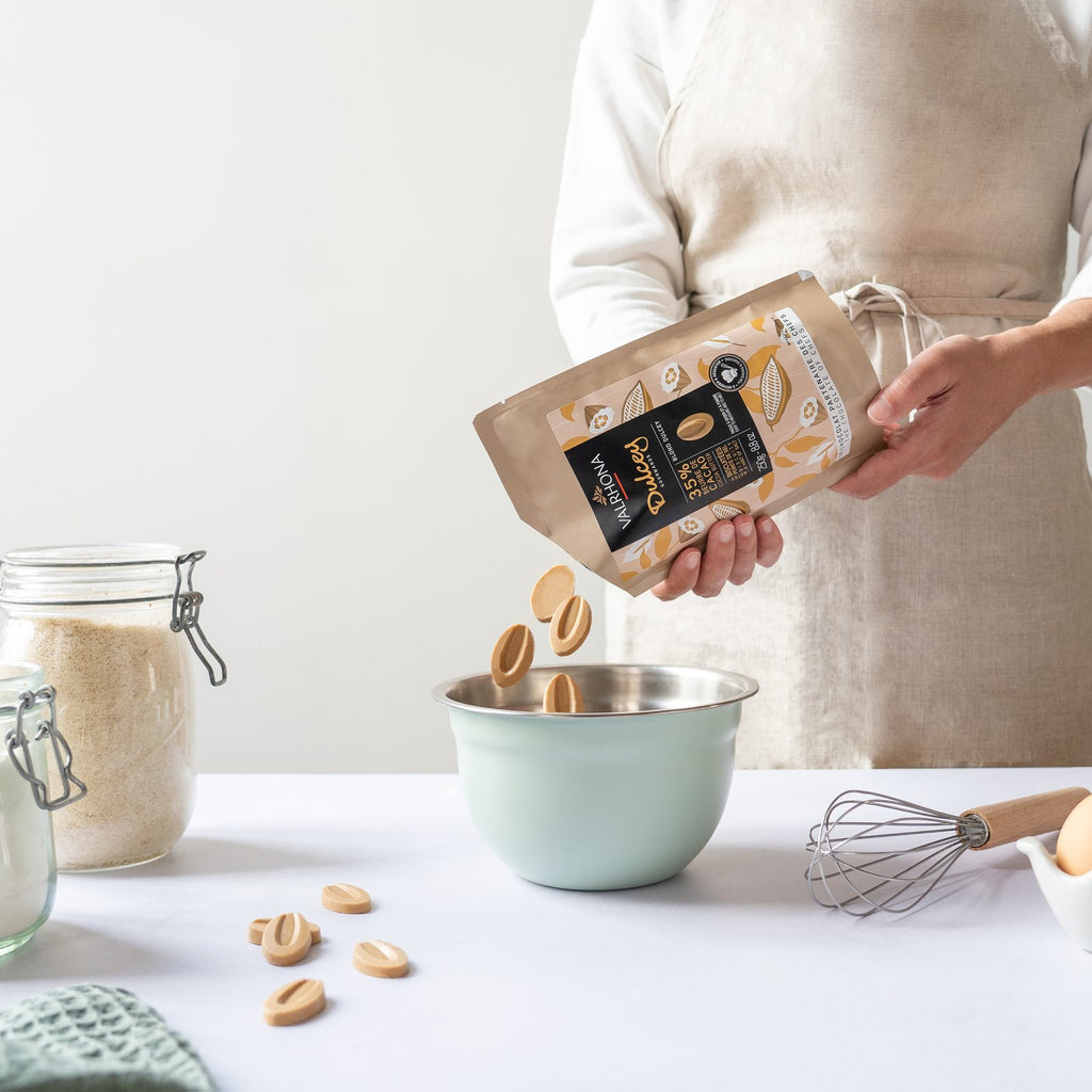 Pouring Valrhona Dulcey 35% blond chocolate feves from the 250g pouch into a bowl