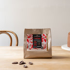 Valrhona Guanaja 70% dark chocolate feves 1kg bag beside a chocolate layer cake