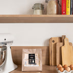 Valrhona Ivoire 35% white chocolate feves bag on a kitchen shelf with jars and cookbooks