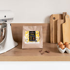 Valrhona Jivara 40% milk chocolate feves bag on a kitchen counter with eggs and wooden boards