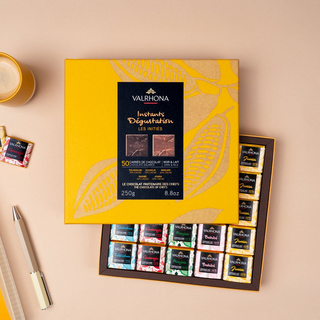 Valrhona 50-piece mixed dark and milk chocolate squares gift box on a desk with notebook and pen
