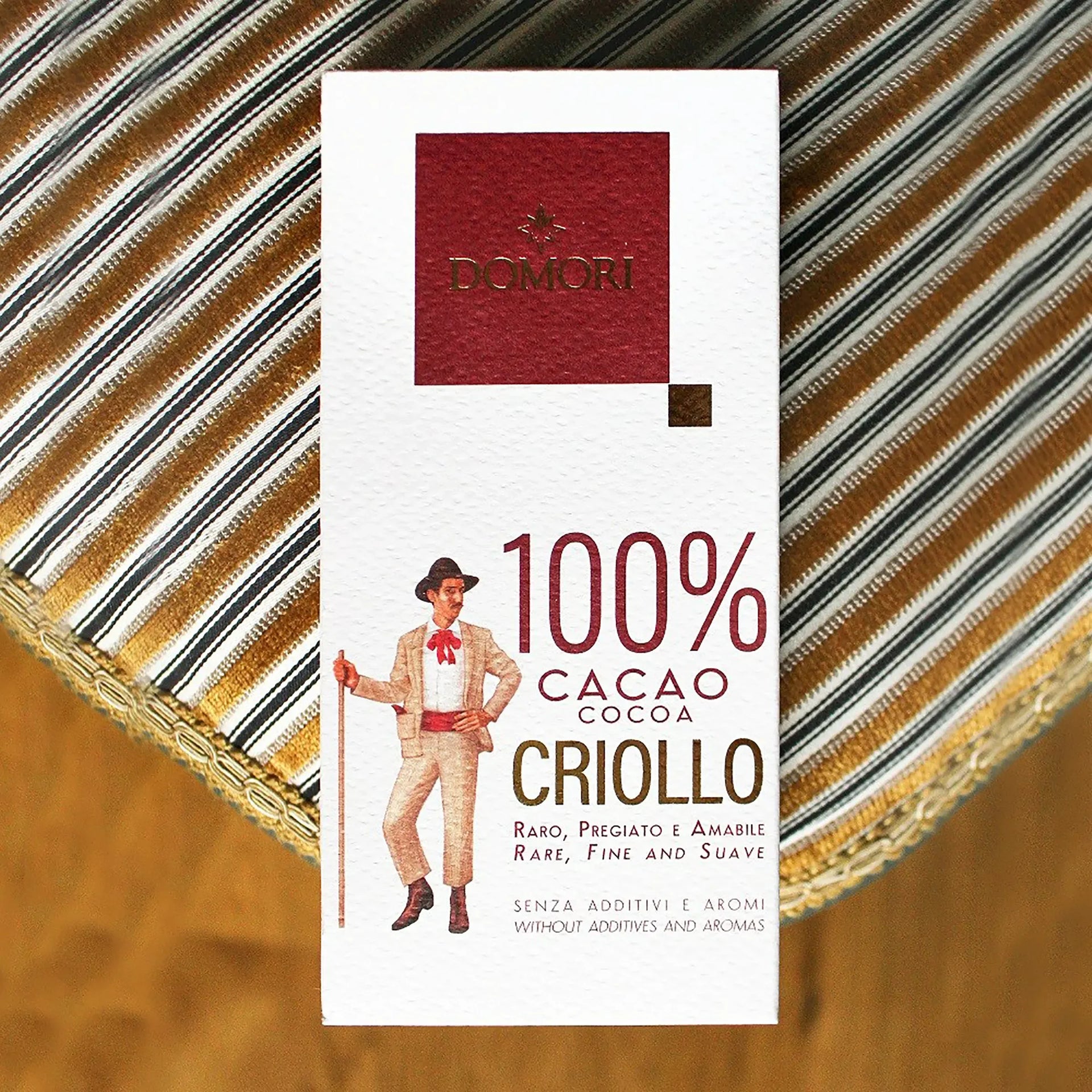 Domori Criollo 100% cacao chocolate bar in white rectangular package with red logo and suited man illustration
