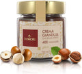 Domori Crema Gianduja hazelnut spread jar with gold lid amid hazelnuts