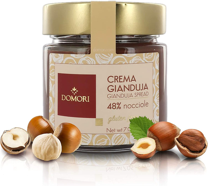 Domori Crema Gianduja hazelnut spread jar with gold lid amid hazelnuts