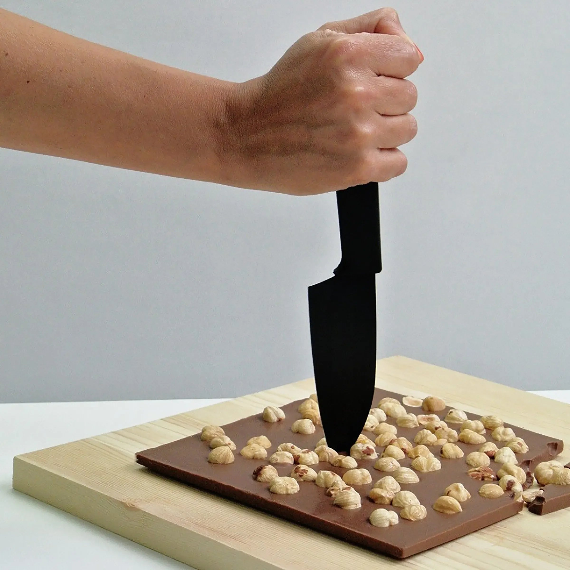 Black knife slicing Domori Quantum Milk Chocolate with Hazelnuts 42%