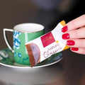 Hand with red nails holds Domori Tartufo Classico chocolate bar, 10 pcs pack