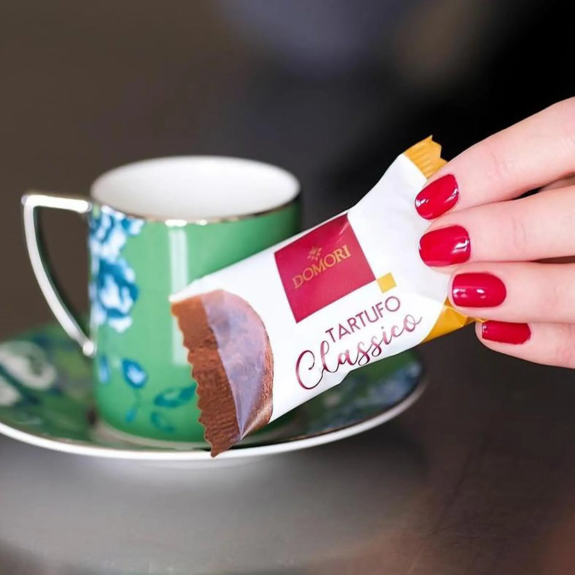 Hand with red nails holds Domori Tartufo Classico chocolate bar, 10 pcs pack