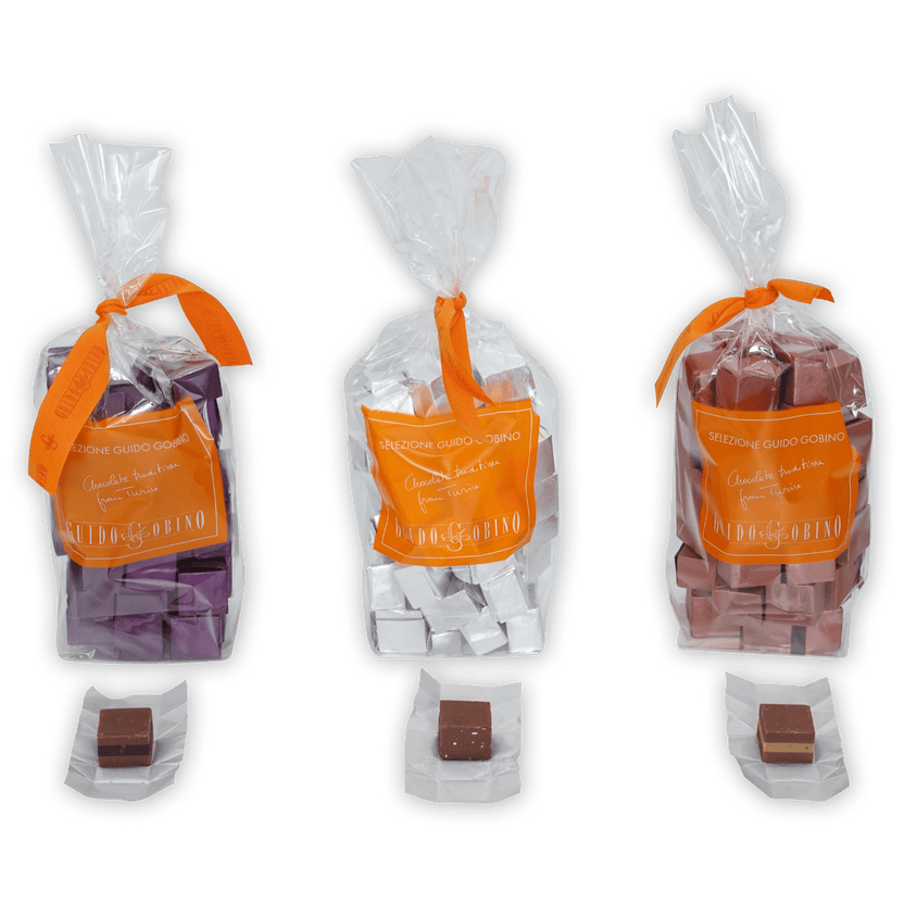 Three Guido Gobino Cremino bags with orange ribbons and chocolates